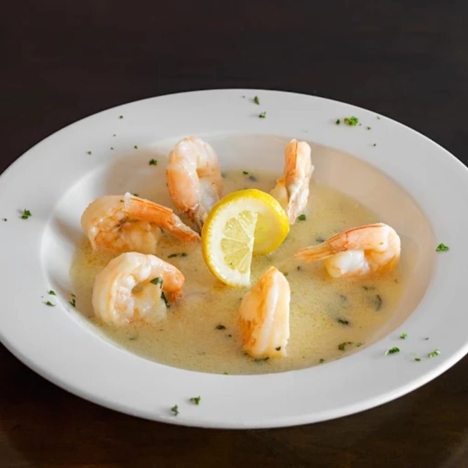 Shrimp scampi with lemon and parsley in a white bowl at Franco's Pizza.